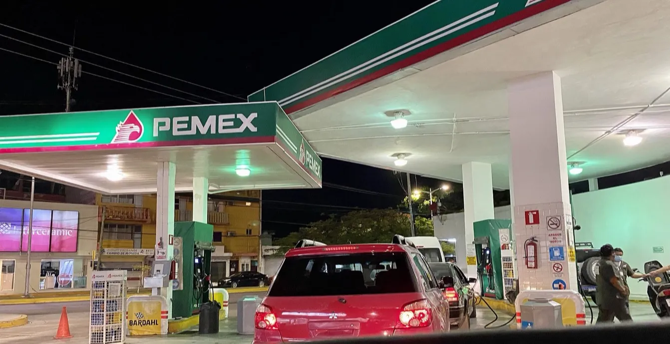 Estación de servicio Pemex de noche con autos cargando gasolina